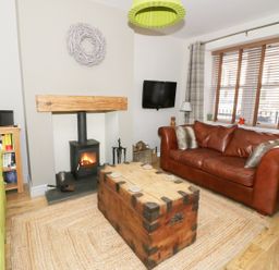 A living room with a green sofa a brown leather sofa wood burning stove and a wooden chest coffee table at Llwyn Onn in Dolwyddelan
