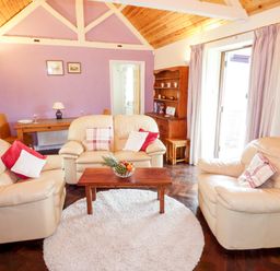 A living room with beige sofas pillows a wooden coffee table and a circular rug at The Packing House in Hanley Castle near Malvern