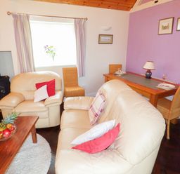 A living room with beige leather sofas wooden coffee table with fruit bowl and a dining table with wicker chairs at The Packing House in Hanley Castle near Malvern