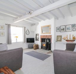 A living room with two grey sofas a fireplace a TV and a model ship at Marsh Villa in Silloth