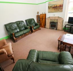 A living room with green sofas and armchair at White Thorns in Haverfordwest