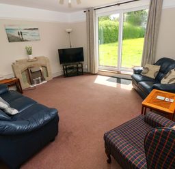 A living room with a television and sofas at White Thorns in Haverfordwest