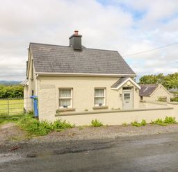 A cream-colored house with a grey roof behind a low wall and a gated driveway at Shandrum Brook in Charleville