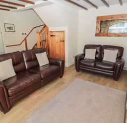 A living room with two brown leather sofas a wooden staircase and a wall mirror at The Mistal in Glanton near Alnwick
