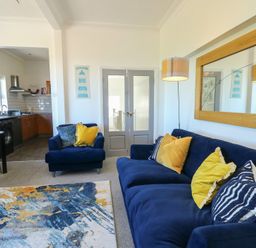 A living room with a blue sofa and open kitchen area at Little Orme View in Llandudno