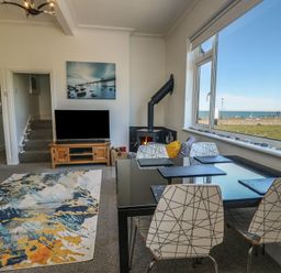 A living room with a tv and dining area at Little Orme View in Llandudno