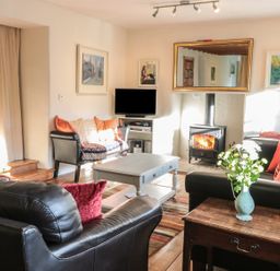 A living room with leather sofas a wood burning stove and a TV at Beulah Cottage Green Bottom near Littledean