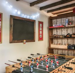 A game room with a foosball table shelves with board games and a blackboard at Beulah Cottage in Green Bottom near Littledean