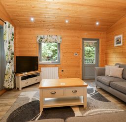 A living room with a sofa, coffee table, and television at Elm Lodge in Ulverston