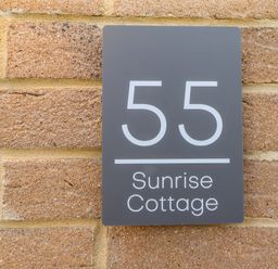 A house nameplate on a brick wall at Sunrise Cottage in Beadnell