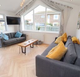 A living room with sofas and a television at Sunrise Cottage Beadnell