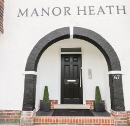 An entrance door under a black painted arch with the text Manor Heath above in Scarborough