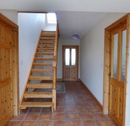 A hallway with tiled floor wooden doors and staircase at The Slate House in Cahersiveen County Kerry