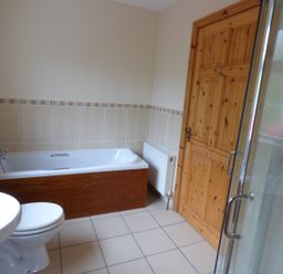 A bathroom with a bathtub toilet sink wooden door and shower at The Slate House in Cahersiveen County Kerry