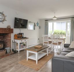 A living room with a fireplace television coffee table dining table and sofa at Flip Flops The Bay near Filey