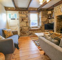 A living room with two sofas a wooden floor a small coffee table and a stone fireplace at Pippin in Lelant
