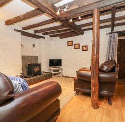 A living room with leather sofas a wood burning stove and a television at Apple Loft in Lostwithiel