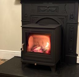 A stove with a fire in a fireplace at Haven in Porthleven