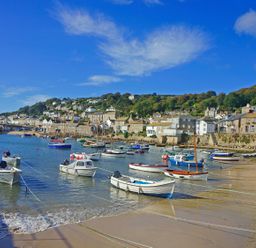 A harbor with boats tied to the shore and houses on a hillside at Calac Cottage in Mousehole