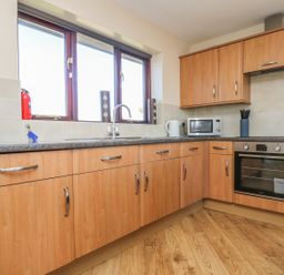 A kitchen with wooden cabinets a countertop microwave oven toaster and a kettle at Surfside in Marazion