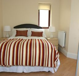 A bedroom with a bed covered in a striped blanket and two lamps on bedside tables at Sea Shore in Marazion