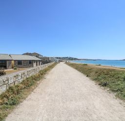 A path along the coast with stone buildings on the left and the sea on the right at Sea Shore in Marazion