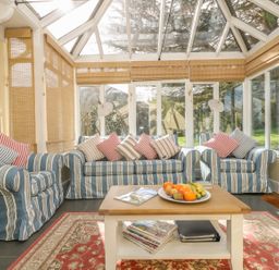 A sunroom with striped sofas and a coffee table with fruit at Boskednan Wartha in Penzance
