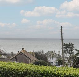 A coastal view with houses trees telephone pole and ocean at Rock Pool in Downderry