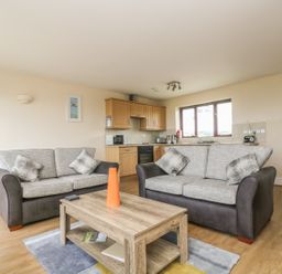 A living room with two sofas a wooden coffee table and an open kitchen at Shoreline in Marazion