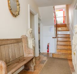 A hallway with a wooden bench statues on either side stairs at 1 Dormer Villas in Portscatho