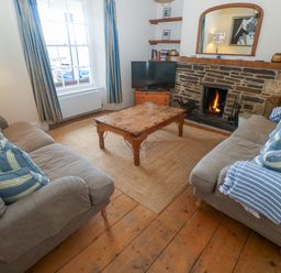 A living room with a coffee table, two sofas, and a fireplace at 1 Dormer Villas in Portscatho