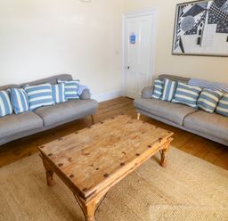 A living room with two sofas and a wooden table at 1 Dormer Villas Portscatho
