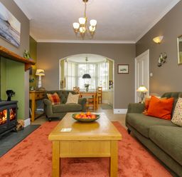 A living room with green sofas orange cushions and a fireplace at Mount View in Marazion