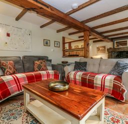 A living room with two sofas covered with red plaid throws and a wooden coffee table at Chenalls Cottage in Helston