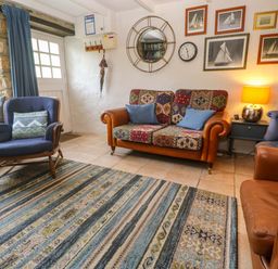 A living room with a sofa and armchair at May Cottage in Pentewan