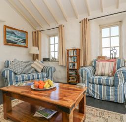 A sitting room with striped armchairs and a wooden coffee table at Boar's House in Penzance