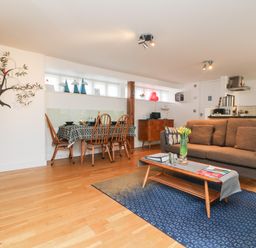 An open living and dining area with a brown sofa and wooden dining table at Ebenezer Cottage in Marazion
