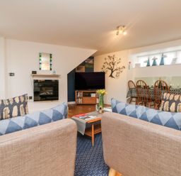 A living room with two brown sofas facing a flat screen TV and a dining table with chairs at Ebenezer Cottage in Marazion