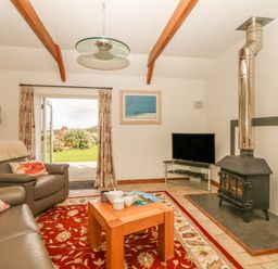 A living room with a wood stove TV leather chairs and a wooden coffee table at Back Of Beyond in St Ives