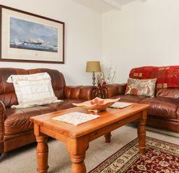 A living room with two brown leather sofas a wooden coffee table a lamp and a framed painting on the wall at Angarrack Farmhouse in Hayle