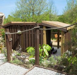 A garden area with wooden fencing and a small deck with chairs and table at Godrevy Cottage in Hayle