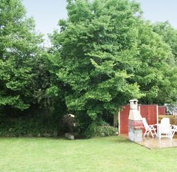 A garden area with lawn trees a red shed barbecue and white patio chairs at Godrevy Cottage in Hayle