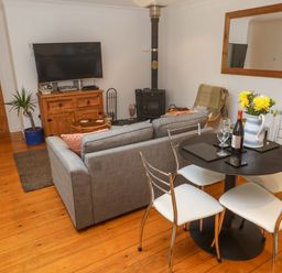 A living room with a sofa, dining table, and television at Godrevy Barn in Hayle