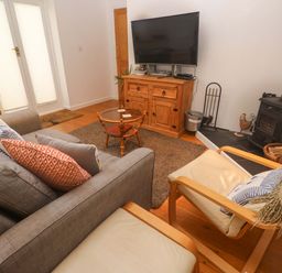 A living room with a sofa coffee table and television at Godrevy Barn in Hayle