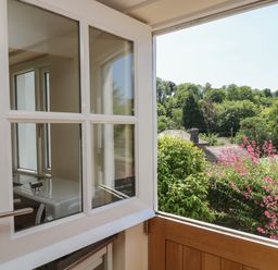 An open door showing a view of trees and pink flowers at Little Hamlin in Rilla Mill Nr Callington