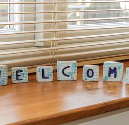 Decorative letters spelling welcome on a wooden windowsill with horizontal blinds at Honeysuckle Cottage in Helston