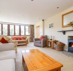 A living room with sofas pillows coffee table fireplace and window at Carne Mill in Manaccan