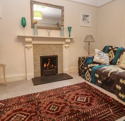 A living room with a fireplace and sofa at Banneth in Helford