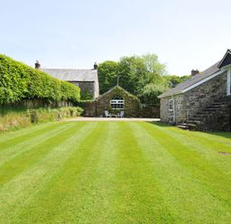 A garden with grass and buildings at Trevenning Chapel Near Port Isaac