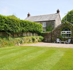 A garden with a house and seating area at Trevenning Chapel Near Port Isaac